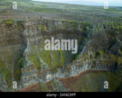 Blick aus der Vogelperspektive auf den Haifoss Wasserfall mit Menschen am Rande einer zerklüfteten Klippe, Selfoss, Südregion, Island. Stockfoto