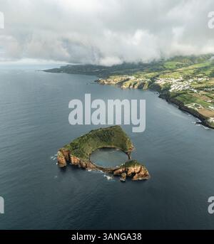 Aus der Vogelperspektive der abgeschiedenen vulkanischen Insel mit lebendigem Grün und azurblauem Wasser, Ilheu de Vila Franca de Campo, Azoren, Portugal. Stockfoto