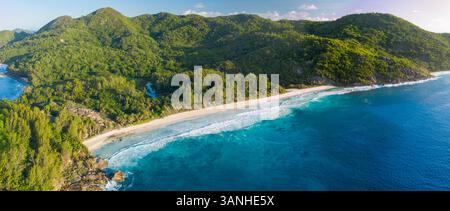 Panoramablick auf Police Bay und Anse Petit Beach mit Hügeln im Hintergrund, Takamaka, Seychellen. Stockfoto