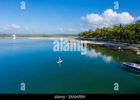 Aus der Vogelperspektive eines blonden Mädchens, das ein Surfbrett entlang der Küste paddelt, Pointe de Flacq, Mauritius. Stockfoto