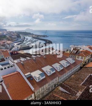 Aus der Vogelperspektive der Gemeinde Angra do Heroismo mit dem kleinen Stadthafen an einem bewölkten Tag, Azoren Inseln, Portugal. Stockfoto