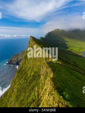 Aus der Vogelperspektive auf einen scharfen Bergrücken entlang der Küste mit Blick auf das Meer auf der Insel Corvo, Azoren, Portugal. Stockfoto