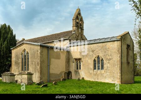 Kelmscott, Oxfordshire - St. George's Churchyard in Kelmscott, wo sich das William Morris Memorial versteckt hinter einem Lorbeerbaum im Oxf befindet Stockfoto