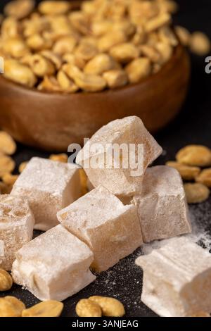 Türkischer Genuss mit Erdnusskernen auf schwarzem Schieferbrett, orientalischen Süßigkeiten aus Zucker und Melasse mit Erdnüssen, Nahaufnahme Stockfoto