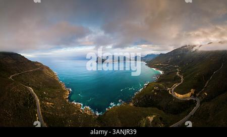 Blick aus der Vogelperspektive auf die zerklüftete Küste mit gewundenen Straßen und majestätischen Bergen in Hout Bay, Kapstadt, Südafrika. Stockfoto