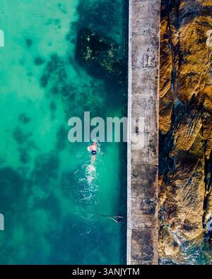 Aus der Vogelperspektive einer Person, die im Gezeitenpool Camps Bay schwimmt, Kapstadt, Südafrika. Stockfoto
