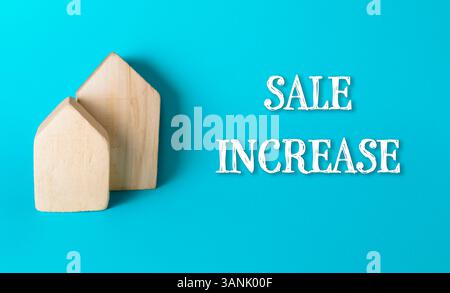Zwei Holzhäuser sind auf blauem Hintergrund mit der Aufschrift „Sale Increase“ darunter Stockfoto