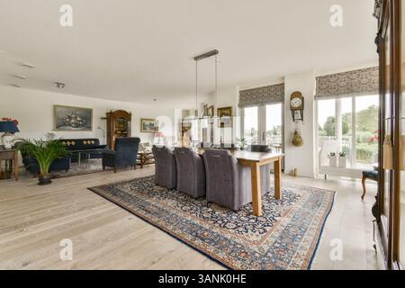 Geräumiges Wohnzimmer mit modernen Möbeln, stilvollem Teppich und viel Tageslicht schaffen eine einladende Atmosphäre zum Entspannen und für Versammlungen. Stockfoto