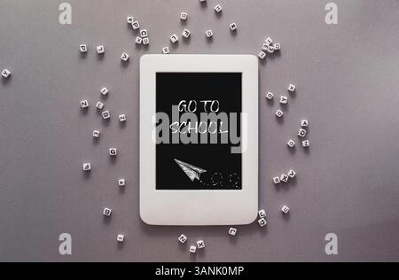 Weiße Tablette mit den Worten "gehe zur Schule" darauf. Die Tablette ist von einem Stapel weißer Würfel umgeben Stockfoto