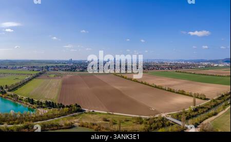 Panoramablick der Drohne auf Ackerland und Bezirk 22, Donaustadt, Wien in der Ferne, Gerasdorf, Niederösterreich, Österreich. Stockfoto