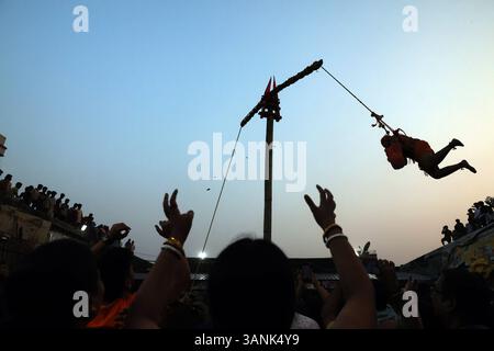 Chadak Festival, in Kalkutta, Indien die Menschen warten darauf, Opfer von einem hinduistischen Anhänger zu erhalten, der während des Chadak-Rituals am 14. April 2025 in Kalkutta, Indien, an einem Seil hängt. Das Chadak-Ritual ist eine einzigartige und lebendige Tradition, die in Westbengalen beobachtet wird, insbesondere während des Charak Puja, einem Volksfest zu Ehren von Lord Shiva. Dazu gehört, dass Gläubige waghalsige Handlungen wie Body Piercing, Hakenschaukeln oder das Gehen auf Feuer als Opfer von Buße und Hingabe ausführen. Das Ritual findet in der Regel am letzten Tag des bengalischen Kalenders statt und zieht große Menschenmassen an. Kalkutta Stockfoto