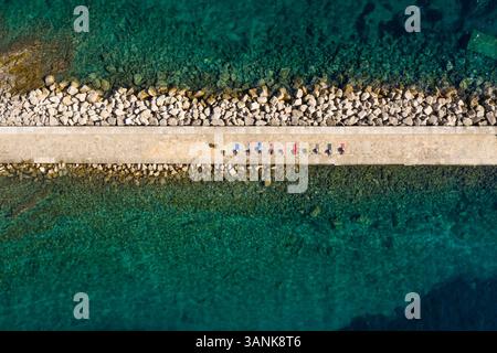 Aus der Vogelperspektive einer Gruppe, die Yoga am künstlichen Pier, Veli Lošinj, Kroatien praktiziert. Stockfoto