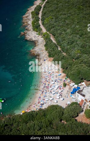 Blick aus der Vogelperspektive auf den Ambrela-Strand mit türkisfarbenem Meer und überfüllten Sonnenschirmen, Pula, Istrien, Kroatien. Stockfoto