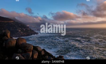 Aus der Vogelperspektive auf die zerklüftete Küste mit majestätischen Bergen und ruhigen Wolken, Chapmans Peak, Noordhoek, Westkap, Südafrika. Stockfoto