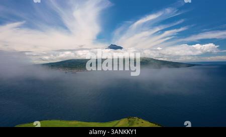 Aus der Vogelperspektive auf die malerische Insel Faial mit dem majestätischen Pico-Berg und dem ruhigen Meer, Horta, Azoren, Portugal. Stockfoto