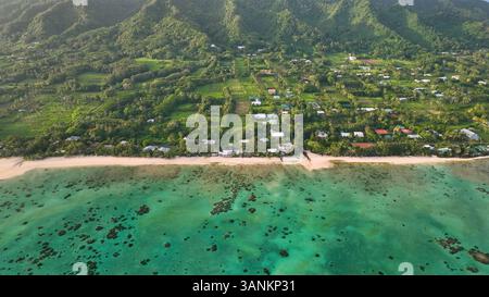 Blick aus der Vogelperspektive auf tropischen Strand und Dorf mit üppigem Grün und Bergen, Avarua, Cook Islands. Stockfoto