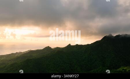 Aus der Vogelperspektive auf atemberaubende Berge und üppigen Wald bei einem lebhaften Sonnenuntergang mit Wolken, Rarotonga, Cook Islands. Stockfoto