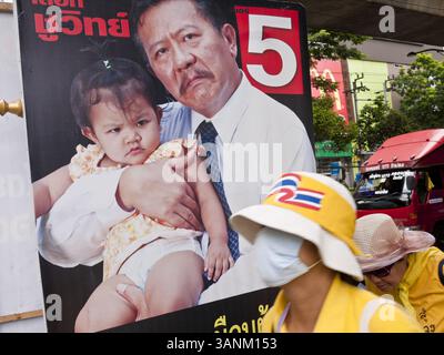 22. Juni 2011 - Bangkok, Thailand - Thai Yellow Shirts, die ein „Nein“ bei der Wahl fordern, gehen an einem Wahlkampfplakat in Bangkok, Thailand vorbei. Yingluck Shinawatra, Führer der Pheua Thai Partei, kandidiert gegen den amtierenden Premierminister Abhisit Vejjajiva, den Vorsitzenden der Demokratischen Partei. Yingluck ist die jüngste Schwester des ehemaligen Premierministers Thaksin Shinawatra, der 2006 durch einen Militärputsch abgesetzt wurde. Yingluck ist derzeit führend in Meinungsumfragen und ist der Demokratischen Partei weit voraus, die Thailand in der einen oder anderen Form den Großteil der letzten 60 Jahre regiert hat. Foto von Stockfoto
