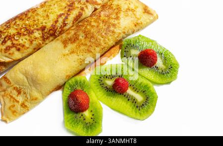 Crepes oder dünne Pfannkuchen mit Käse, Beeren und Früchten. Hausgemachte dünne Pfannkuchen, russische Blini oder französische Crepes mit Hüttenkäse und Kiwi. Lecker ho Stockfoto