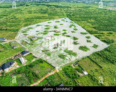 Blick aus der Vogelperspektive auf üppiges Ackerland und Wohnhäuser inmitten grüner Vegetation und ruhigem Wasser, Greater Port Harcourt, Nigeria. Stockfoto