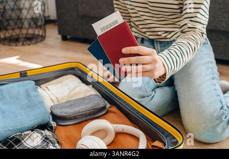 Junge Reisende, die auf dem Boden sitzt und Koffer packt, bereitet sich auf die Sommerferien vor... Stockfoto