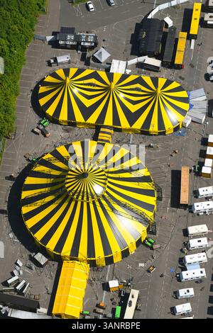 Luftaufnahme des farbenfrohen Zirkuszelt mit gelben und schwarzen Streifen in städtischer Umgebung, Mönchengladbach, Nordrhein-Westfalen, Deutschland. Stockfoto