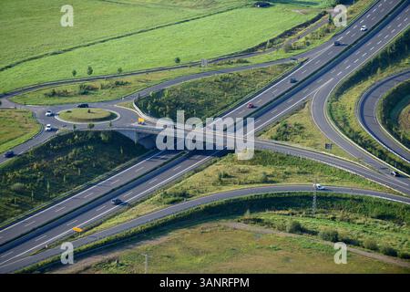 Aus der Vogelperspektive auf eine schöne urbane Kreuzung mit Kreisverkehr und Autobahn umgeben von Grün und Feldern, Weimar (Lahn), Hessen, Deutschland. Stockfoto