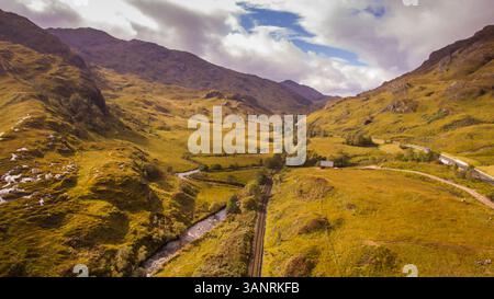 Aus der Vogelperspektive auf die Landschaft in der Nähe von Glenfinnan in Schottland mit der Eisenbahn, auf der die berühmte Jacobitendampfbahn jeden Tag vorbeifährt. Stockfoto