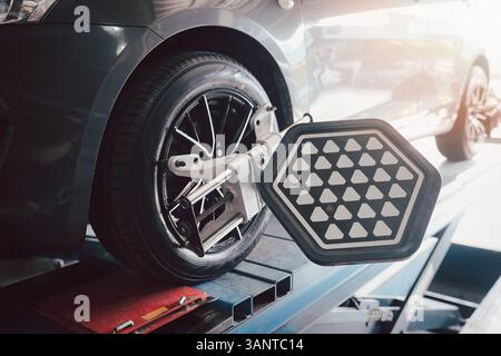 Die Radwuchtmaschine des Autos wird mit einem Laserreflektor kalibriert, der an jedem Reifen angebracht ist, um die mittlere Fahreinstellung einzustellen. Auto im Auto-Service. Auswuchtreifen Radmaschine. Stockfoto