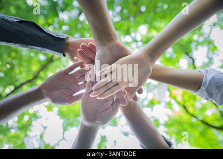 Wurmperspektive auf Menschen, die ihre Hände zusammenlegen. Handstapel. Konzept für Einheit und Teamarbeit. Das Team legt die Hände im Kreis zusammen. Stockfoto