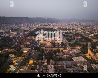 Blick aus der Vogelperspektive auf das wunderschöne Stadtbild mit dem historischen Stadtpalast und den bunten Dächern in der Abenddämmerung, Jaipur, Indien. Stockfoto