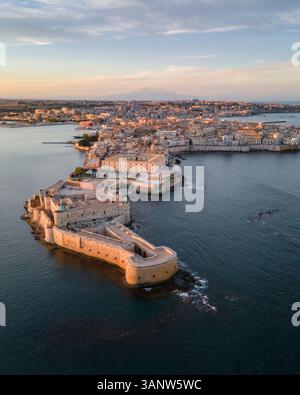 Blick aus der Vogelperspektive auf das historische Schloss maniace auf der Insel ortigia bei Sonnenuntergang mit einer wunderschönen Küste und ruhigem Meer, Syrakus, Italien. Stockfoto