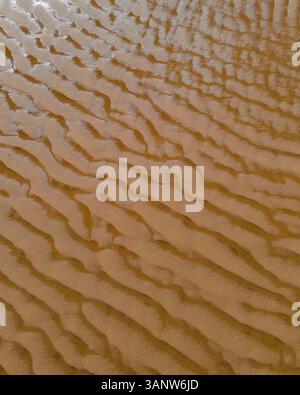 Aus der Vogelperspektive wunderschöne Sandmuster und -Strukturen an einem ruhigen Strand, San Vicente de la Barquera, Spanien. Stockfoto