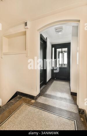 Ein stilvoller Inneneingang mit eleganten schwarzen Türen und poliertem Boden, der eine elegante Atmosphäre im Eingangsbereich schafft. Stockfoto