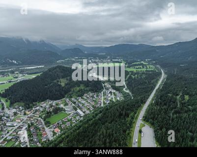 Aus der Vogelperspektive auf eine malerische Autobahn, die sich durch die wunderschönen österreichischen Alpen mit Bergen und einer malerischen Stadt schlängelt, Reutte, Österreich. Stockfoto