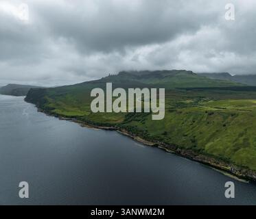 Blick aus der Vogelperspektive auf die zerklüftete Küste und üppige Hügel, die auf die ruhige Nordsee treffen, Portree, Schottland. Stockfoto