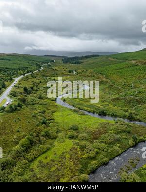 Aus der Vogelperspektive auf den sich windenden Fluss und die Straße durch das üppige grüne Tal und die Hügel, Portree, Schottland. Stockfoto
