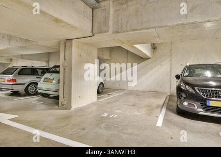 Eine saubere, gut beleuchtete, moderne Tiefgarage, in der verschiedene geparkte Fahrzeuge ausgestellt sind und ein organisierter Platz für städtische Parkmöglichkeiten geschaffen wird. Stockfoto