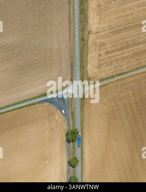 Blick aus der Vogelperspektive auf wunderschöne landwirtschaftliche Felder und eine Straßenkreuzung umgeben von Bäumen, Son, Frankreich. Stockfoto