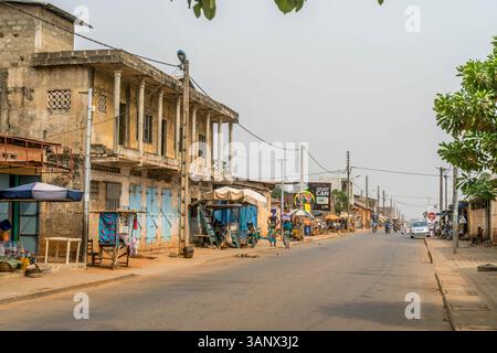 Straße in Porto-Novo, Benin, mit Armut, Geschäften, armen Nachbarschaften und Einheimischen, die entlang der Straße laufen. Stockfoto
