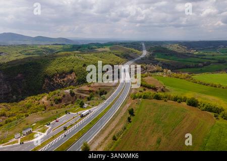 Luftaufnahme von Fahrzeugen auf der Autobahn zwischen den Bergen in Taxiarchis, Westmakedonien, Griechenland. Stockfoto