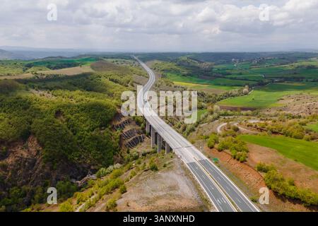 Luftaufnahme von Fahrzeugen auf der Autobahn zwischen den Bergen in Taxiarchis, Westmakedonien, Griechenland. Stockfoto