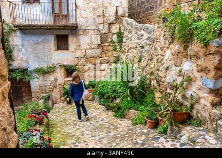 Touristenfrau, die durch die engen Kopfsteinpflasterstraßen des hübschen mittelalterlichen Dorfes Valderrobres, Matarrana, spaziert. Stockfoto