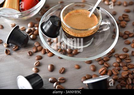 Espresso-Kaffee in einer Glasschale auf einer Holzbank in einer Küche mit Behälter mit Kapseln. Von oben erhobene Aussicht. Stockfoto