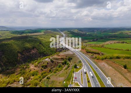 Luftaufnahme von Fahrzeugen auf der Autobahn zwischen den Bergen in Taxiarchis, Westmakedonien, Griechenland. Stockfoto