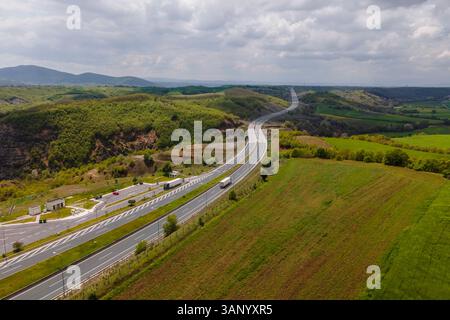 Luftaufnahme von Fahrzeugen auf der Autobahn zwischen den Bergen in Taxiarchis, Westmakedonien, Griechenland. Stockfoto