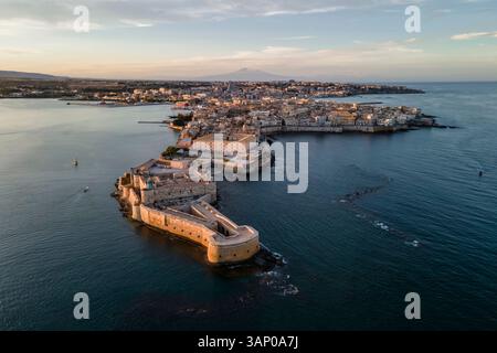 Luftaufnahme der Insel Ortigia und des Schlosses Maniace mit dem Ätna bei Sonnenuntergang in Syrakus, Sizilien, Italien. Stockfoto