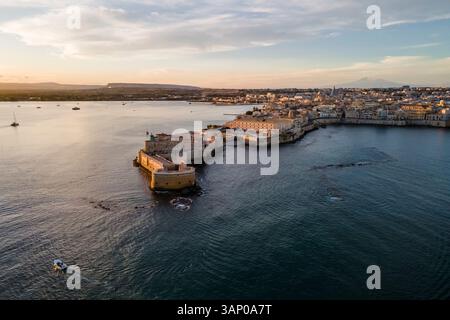 Luftaufnahme der Insel Ortigia und des Schlosses Maniace mit dem Ätna bei Sonnenuntergang in Syrakus, Sizilien, Italien. Stockfoto