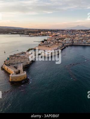 Luftaufnahme der Insel Ortigia und des Schlosses Maniace mit dem Ätna bei Sonnenuntergang in Syrakus, Sizilien, Italien. Stockfoto