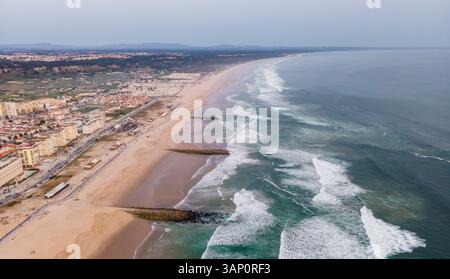 Luftaufnahme der Costa da Caparica Landschaft bei Sonnenuntergang, Blick auf den majestätischen Strand mit rauem Atlantischen Ozean, der an der Küste rollt, Setubal, Portugal. Stockfoto